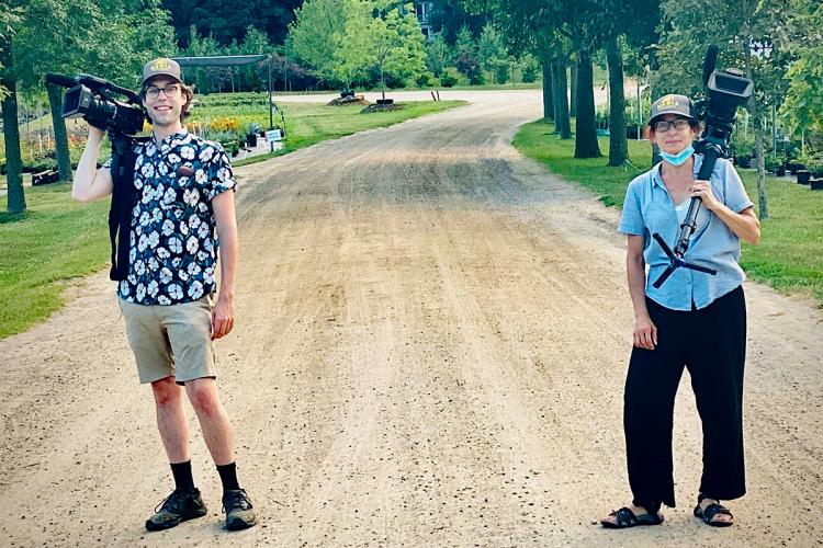 Two people with cameras standing six feet apart outdoors.