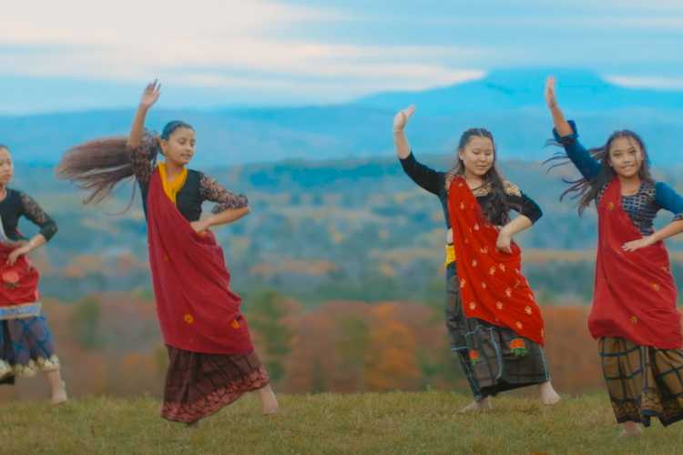 Still from Milan Magar's film of a performance of 4 girls dancing in red saris in a mountain setting