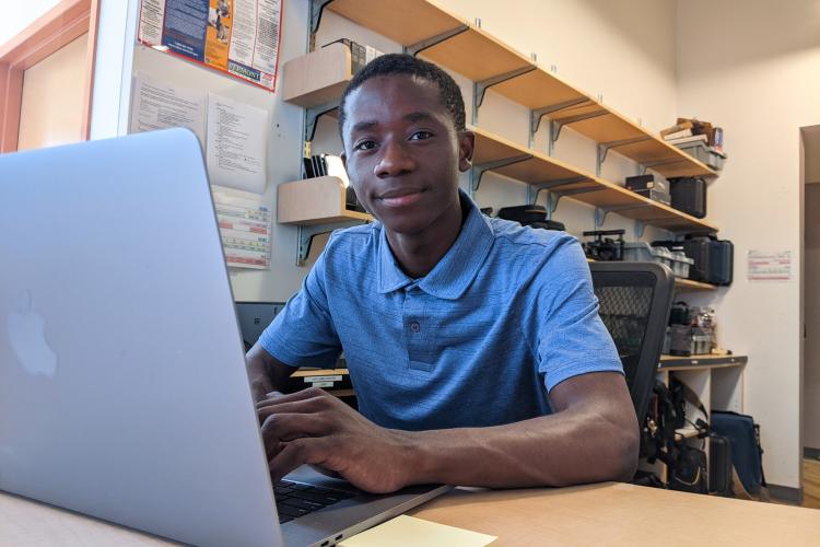 Patient sitting at the gear desk looking up from his laptop.