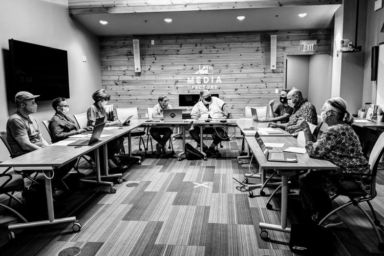 Media Factory board members sit around a u shaped table, wearing face masks.