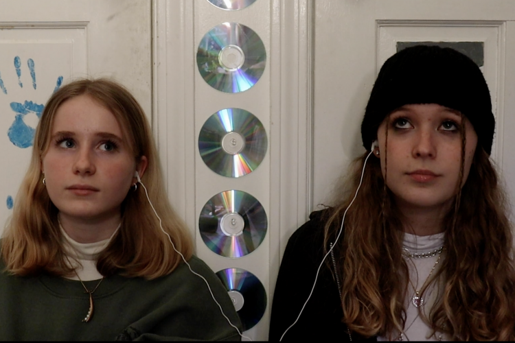 Still from Melting Ice of two teenage girls listening to music side by side