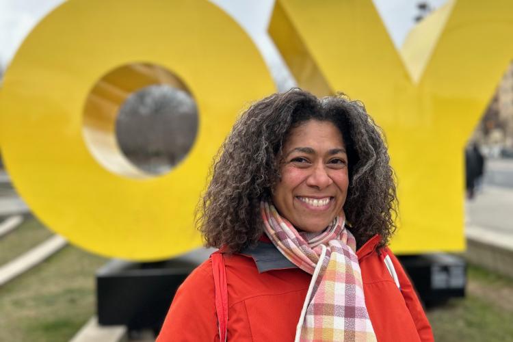 Kendra smiling in a bright red coat in front of large letters "OY."