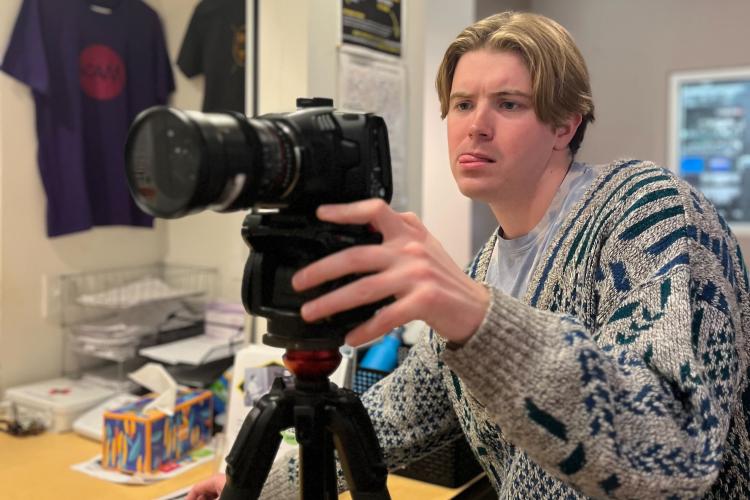 Coleman looks at the screen of a video camera on a tripod.