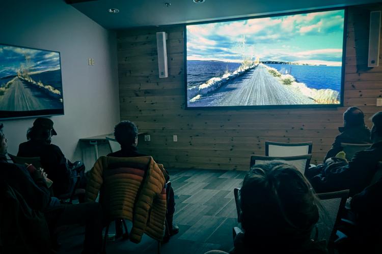a room full of people watching a video of a bicycle ride on the causeway