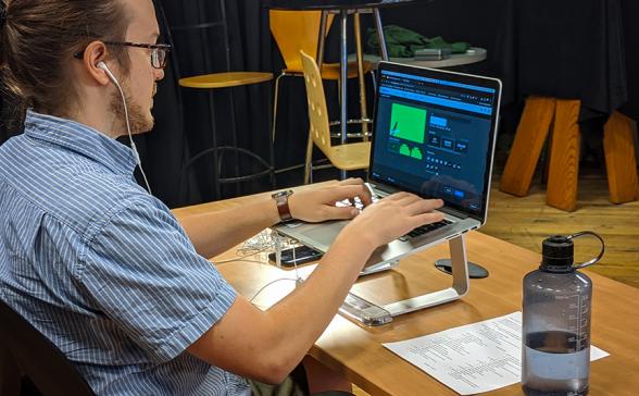 a man sets up an online webinar with a laptop