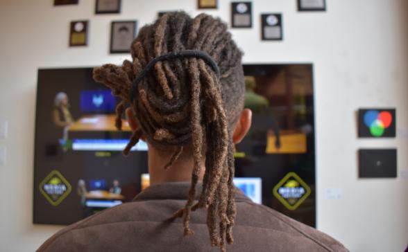 View of a person with dreadlocks watching a television