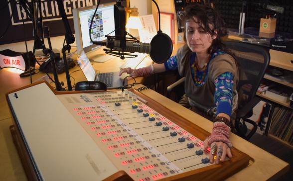 a person in the radio station, adjusting the sound board