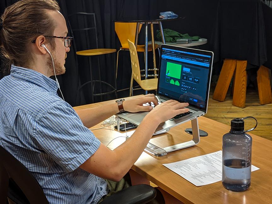 a man sets up an online webinar with a laptop