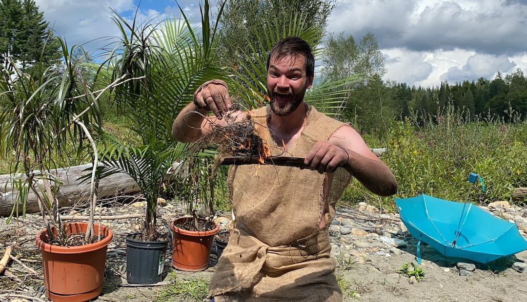 Chuck holds a smoking piece of wood, excited to have started a fire