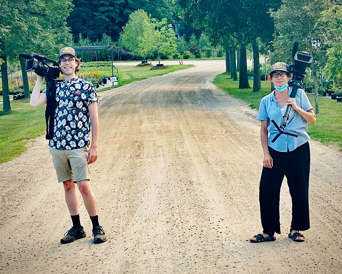 Two people with cameras standing six feet apart outdoors.