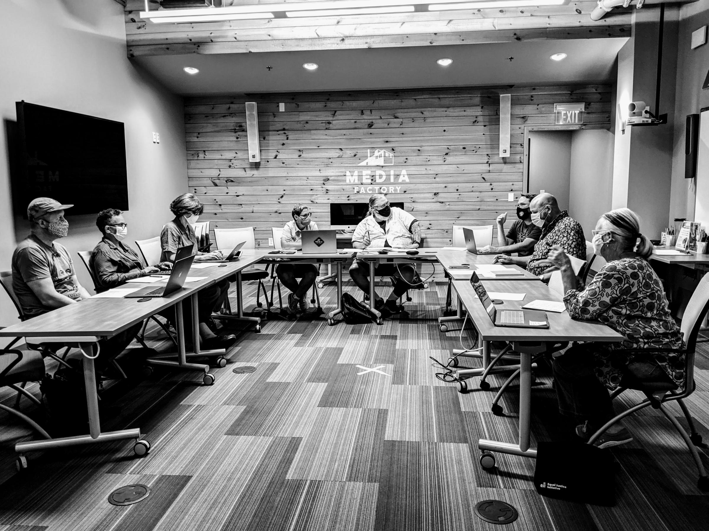 Media Factory board members sit around a u shaped table, wearing face masks.