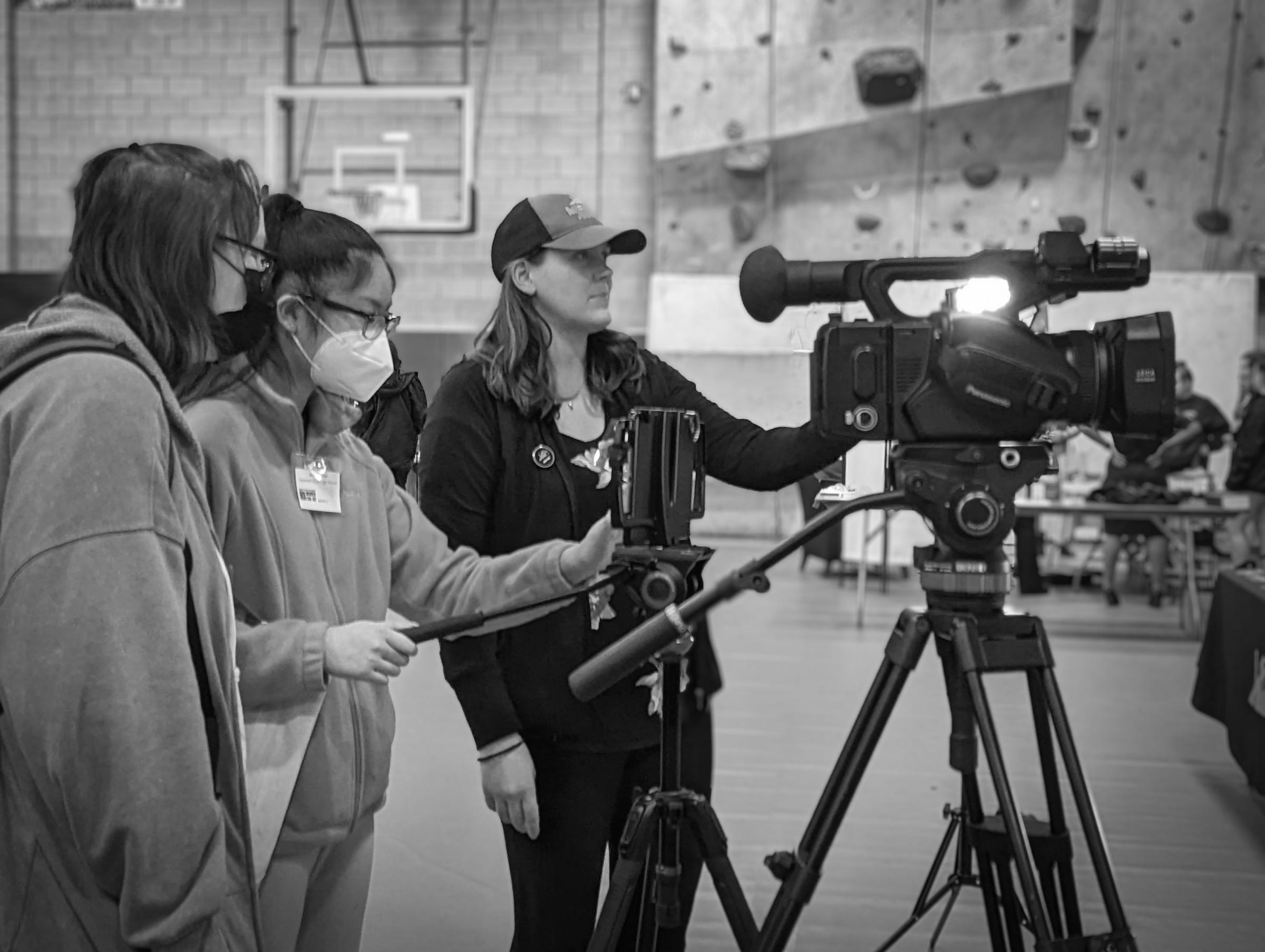 Marcy shows two girls how to operate a video camera