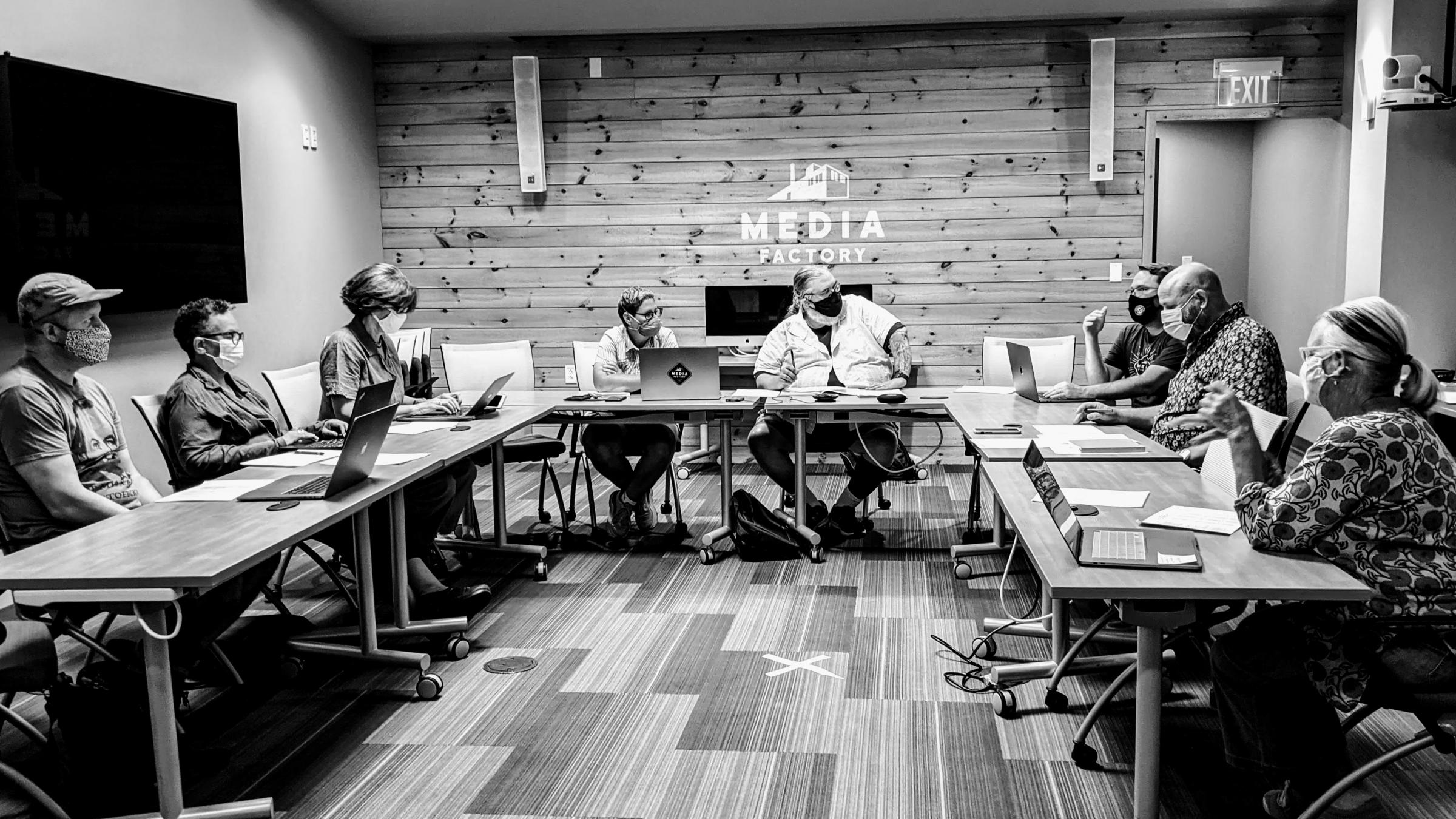 Board members sit around a table in the Media Factory at a monthly meeting.