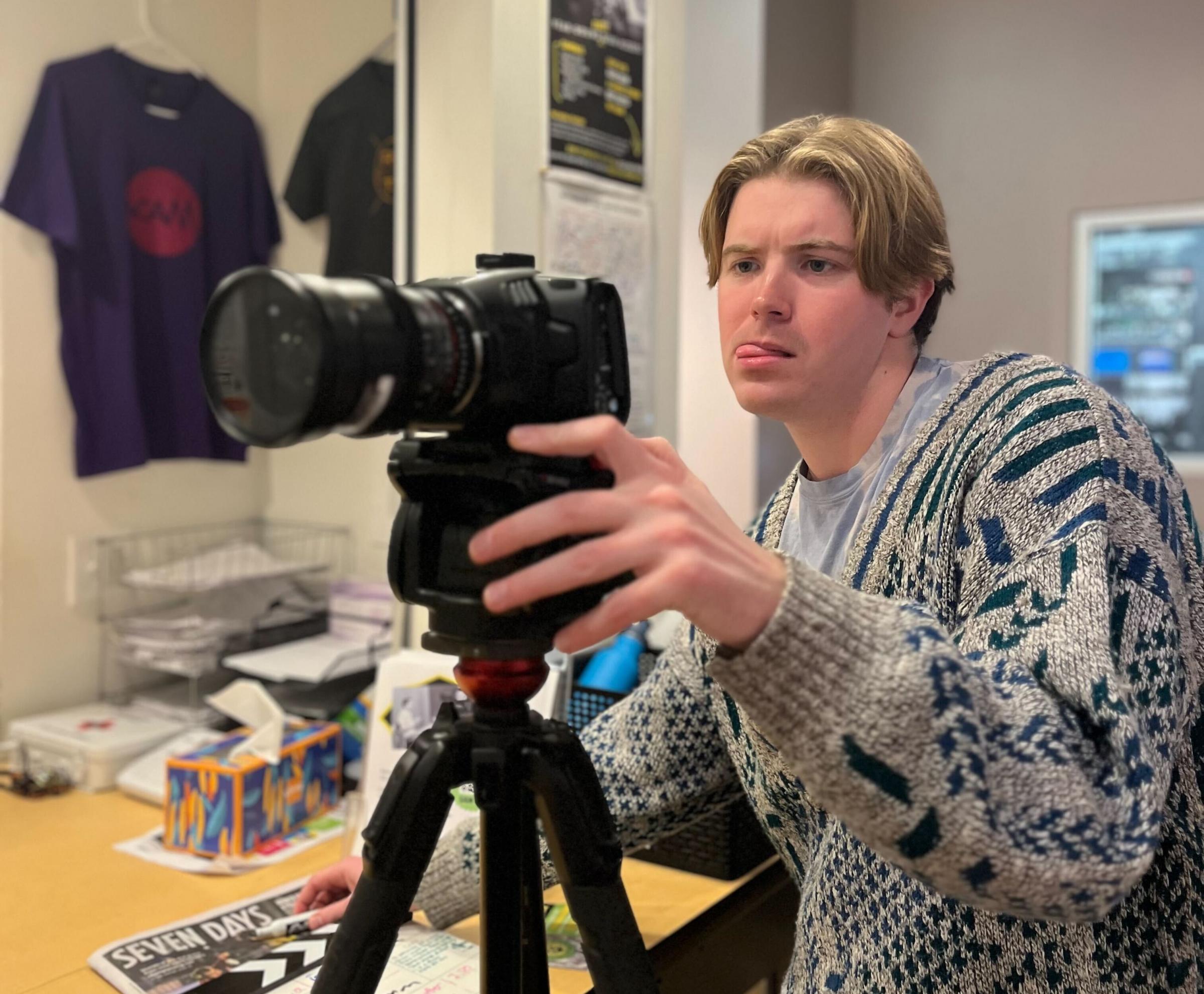 Coleman looks at the screen of a video camera on a tripod.